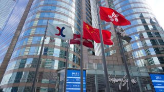 The Chinese and Hong Kong flags flutter as screens display the Hang Seng Index outside the Exchange Square complex, which houses the Hong Kong Stock Exchange, on January 21, 2021 in Hong Kong, China.