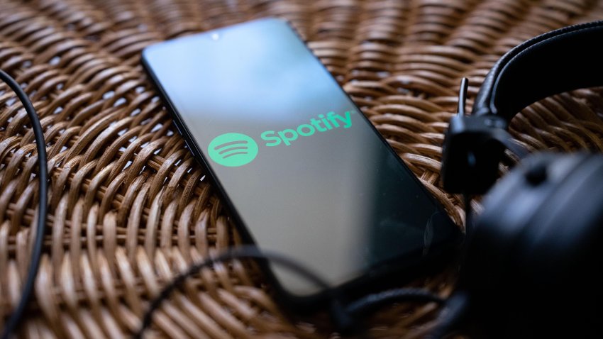 Headphones connected to a mobile phone with the logo of Spotify on its screen