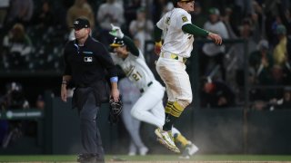 Athletics Luis Urías, right, slides into home safely to score the game winning run against the Texas Rangers during the ninth inning of a baseball game Thursday, April 24, 2025, in West Sacramento, Calif. (AP Photo/Scott Marshall)