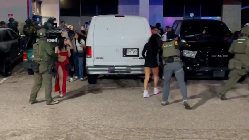Law enforcement agents arresting people outside of a building.