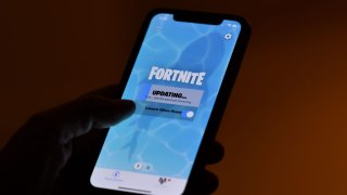 This illustration picture shows a person waiting for an update of Epic Games’ Fortnite on their smartphone in Los Angeles on August 14, 2020.