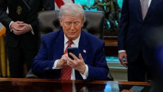 U.S. President Donald Trump handles a cellphone after it rang while he was speaking on the day he signs an executive order at the White House in Washington, D.C., U.S., May 23, 2025.