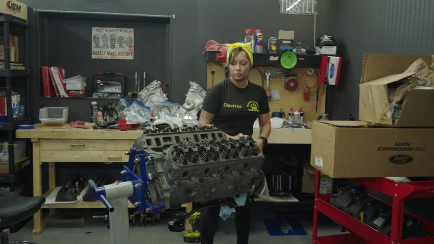 Desiree Hill examines an engine at her auto repair shop, Crown’s Corner Mechanic.