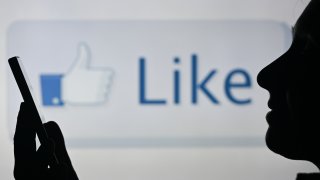 An image of a woman holding a cell phone in front of a LIKE symbol