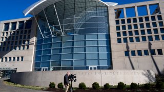 A journalist points his camera at the US Institute of Peace in Washington, DC, on March 18, 2025. Cost-slashers of US President Donald Trump seized control on March 17 of the institute, ousting the leader of the taxpayer-funded center for conflict resolution created by Congress in 1984. (Photo by ROBERTO SCHMIDT / AFP) (Photo by ROBERTO SCHMIDT/AFP via Getty Images)
