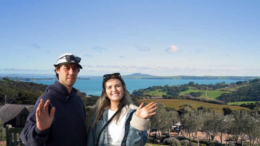 Phoebe Merrick and Reuben Sandoy wave to the camera on Waiheke Island in New Zealand