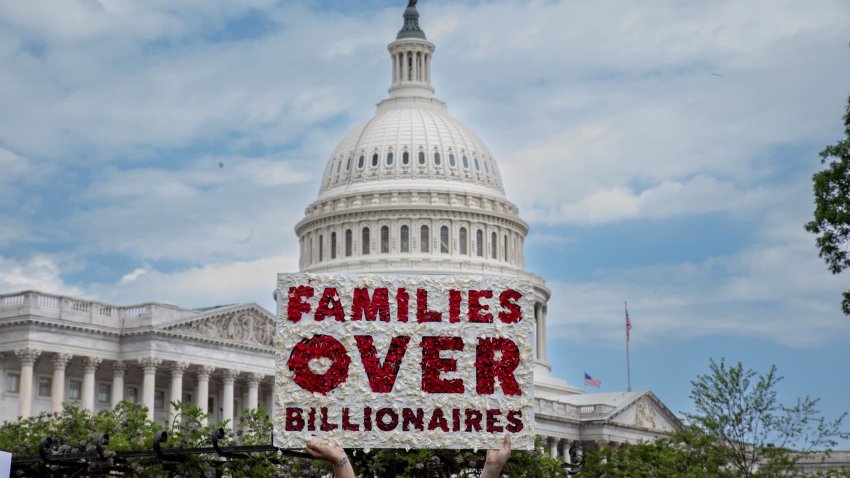A member of MomsRising holds a sign on Capitol Hill to urge lawmakers to reject tax breaks for billionaires and protest cuts to Medicaid and child care on Capitol Hill on May 8 in Washington, D.C.