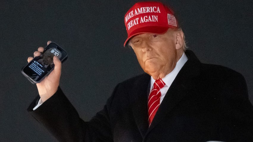 US President Donald Trump disembarks from Air Force One while holding his cellphone with a text message from Roger Stone upon arrival at Joint Base Andrews in Maryland, May 30, 2025, after traveling to Pennsylvania to visit a US Steel plant.