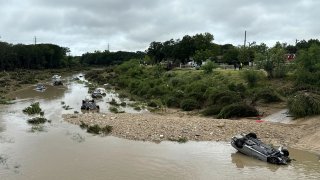 Vehicles sit in the river after being swept away by floodwaters in San Antonio, Tx., Thursday, June 12, 2025. (AP Photo/Lekan Oyekanmi)