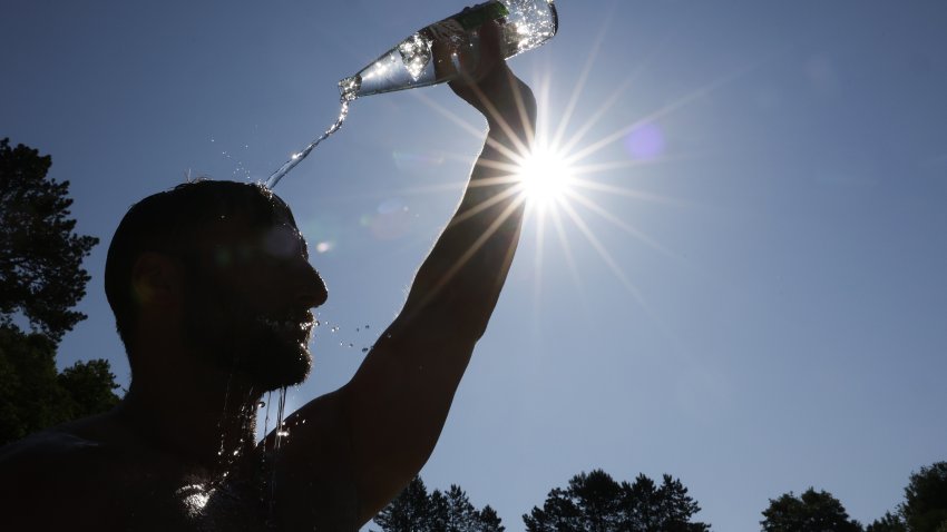 dpatop – 22 June 2025, Baden-Württemberg, Sigmaringen: A man cools down in summer temperatures by pouring a bottle of water over his head. Photo: