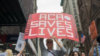 MIDTOWN, NEW YORK, NY, UNITED STATES – 2017/07/29: Participants hold signs while protesting the repeal and replacement of the Affordable Care Act.  At back-to-back rallies in midtown Manhattan, liberal activists rallied against President Trumps intentions to disallow transsexual officers to serve in the U.S. armed forces and then rallied to denounce efforts by the President and Republican politicians to repeal and replace the Affordable Care Act (i.e. Obamacare).