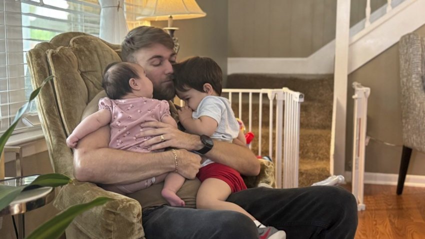 U.S. Marine Corps veteran Adrian Clouatre holds his 3-month-old daughter Lyn and his nearly two old son Noah at their home in Baton Rouge, La. on Tuesday, June 17, 2025. (AP Photo/Stephen Smith)