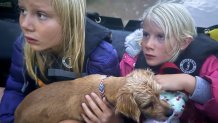 Ella and Grace Sanford and their dog Benjamin ride on a Texas Game Wardens rescue boat after being evacuated from their home after flooding in Uvalde, Texas, on Thursday, July 16, 2026. (Casy Sanford via AP)