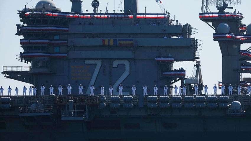 Crew members stand on the deck as the USS Abraham Lincoln Nimitz-class aircraft carrier approaches its homeport at Naval Air Station North Island on return from its historic 10-month deployment on October 8, 2026 as seen from the Port of San Diego in San Diego, California.